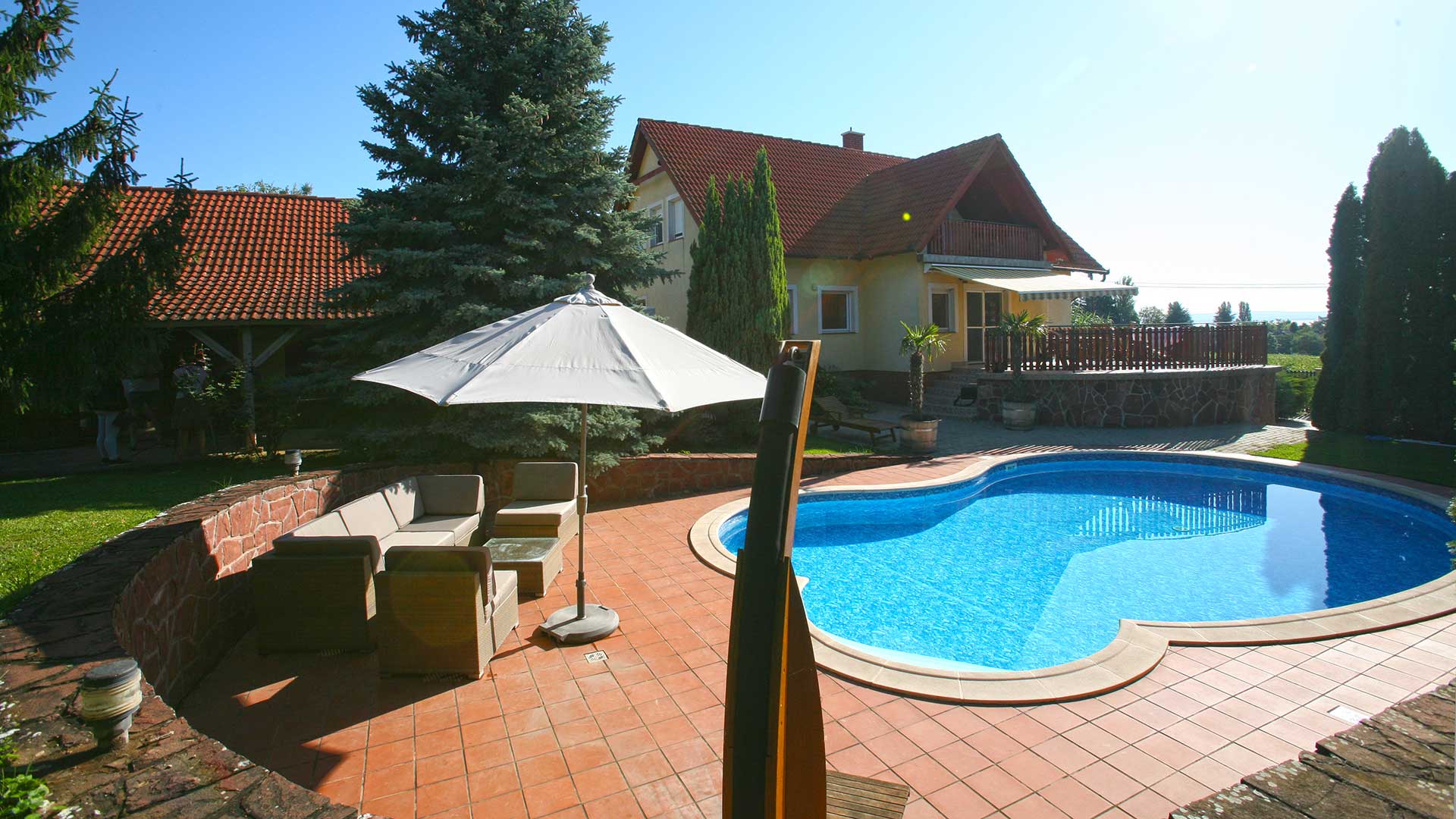 A kép a lakóházat, a melléképületet és a medencét ábrázolja